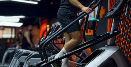 Bahae Sthetic en t-shirt noir et short sur une machine à escaliers en salle de sport