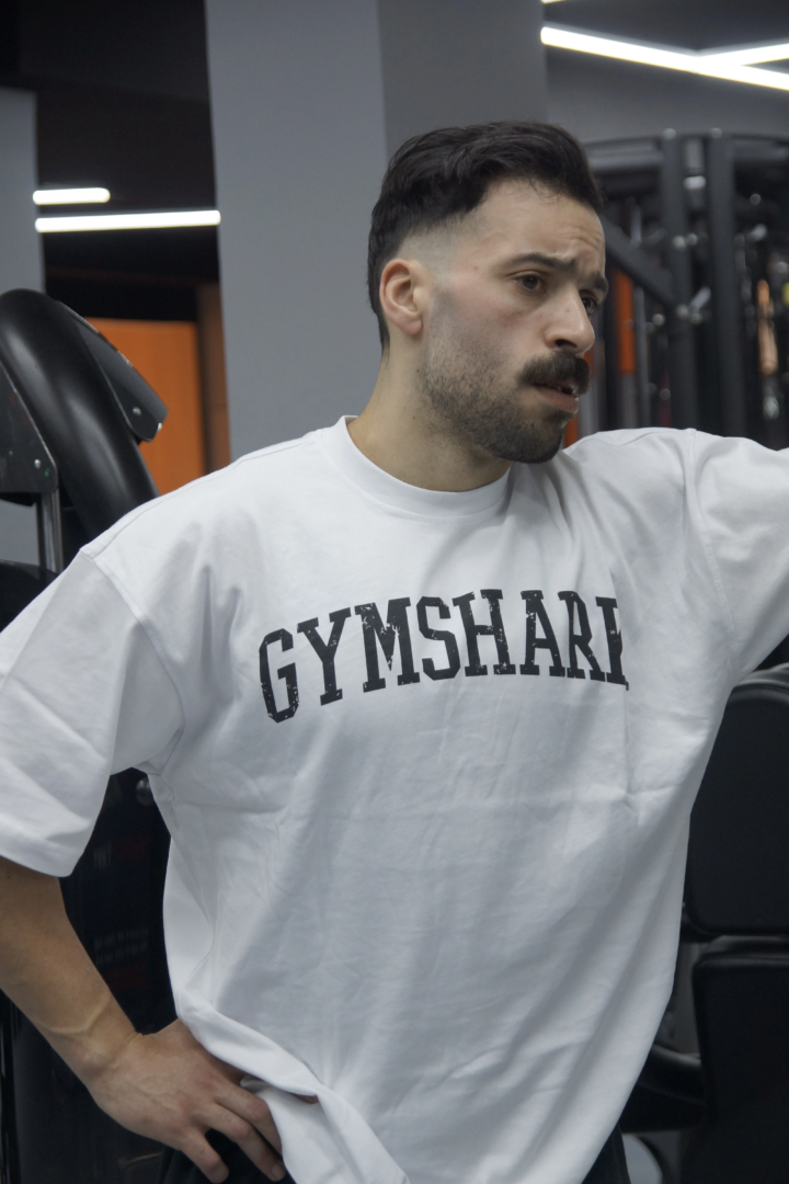 Bahae Sthetic porte un t-shirt blanc ample avec un grand logo Gymshark noir en salle